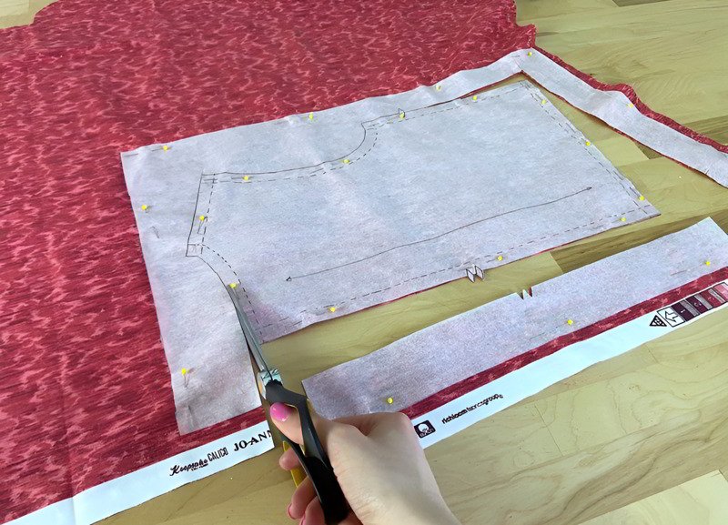 Carefully cutting fabric using pattern and sharp fabric scissors.