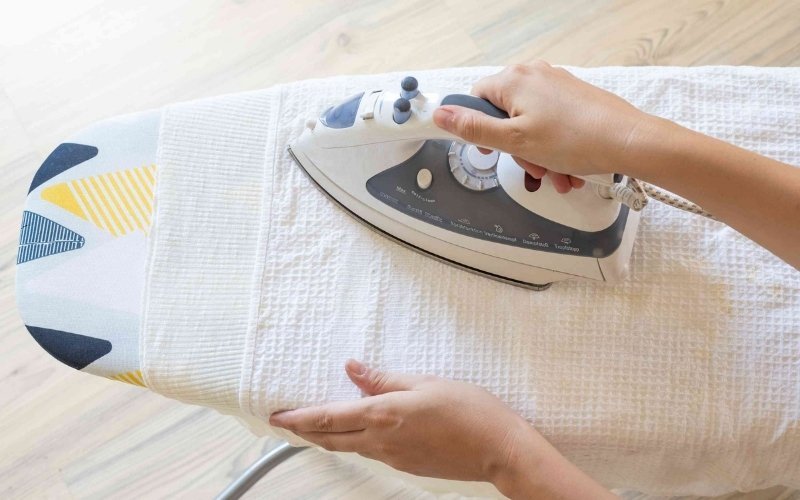 Ironing is using a heated iron with a sliding motion to smooth fabric
