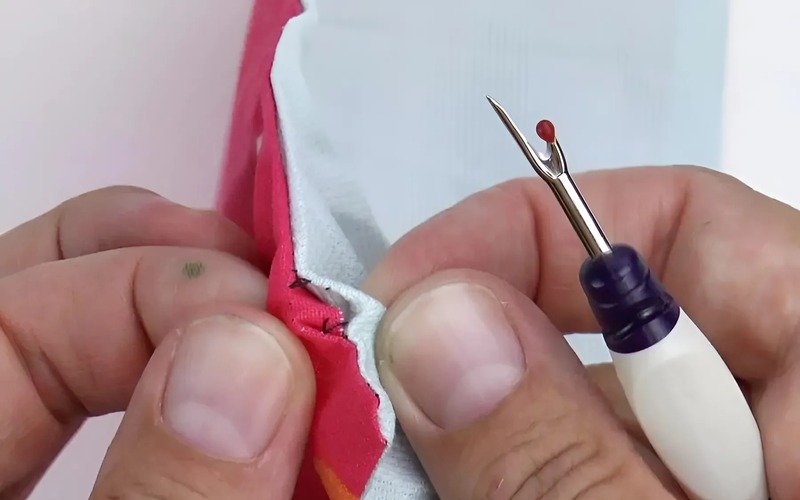 A seam ripper is a small tool. It has a pointed end. We use it to cut and take out stitches you don't want