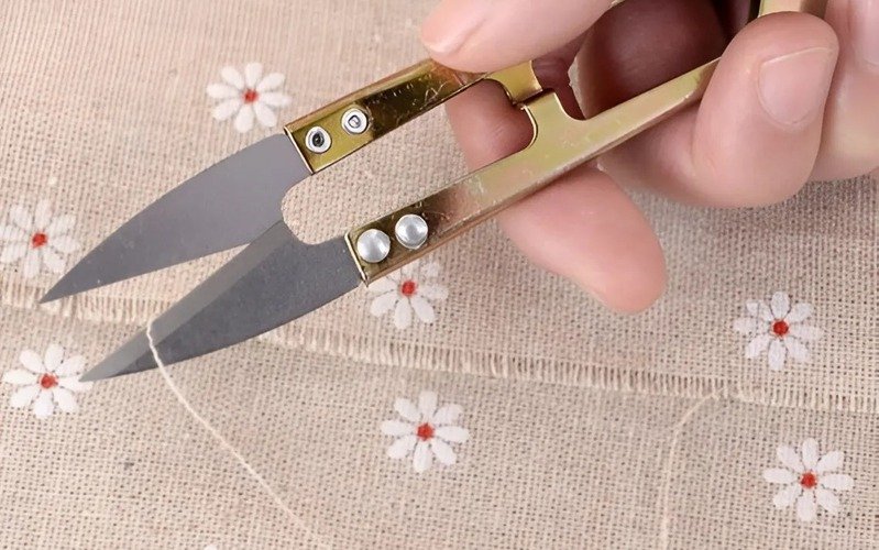 Hold the thread snips, bring the blade tips right to the base of the thread, and give a quick squeeze