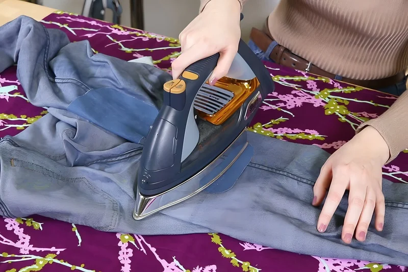 Applying firm pressure with a hot iron to activate the adhesive.
